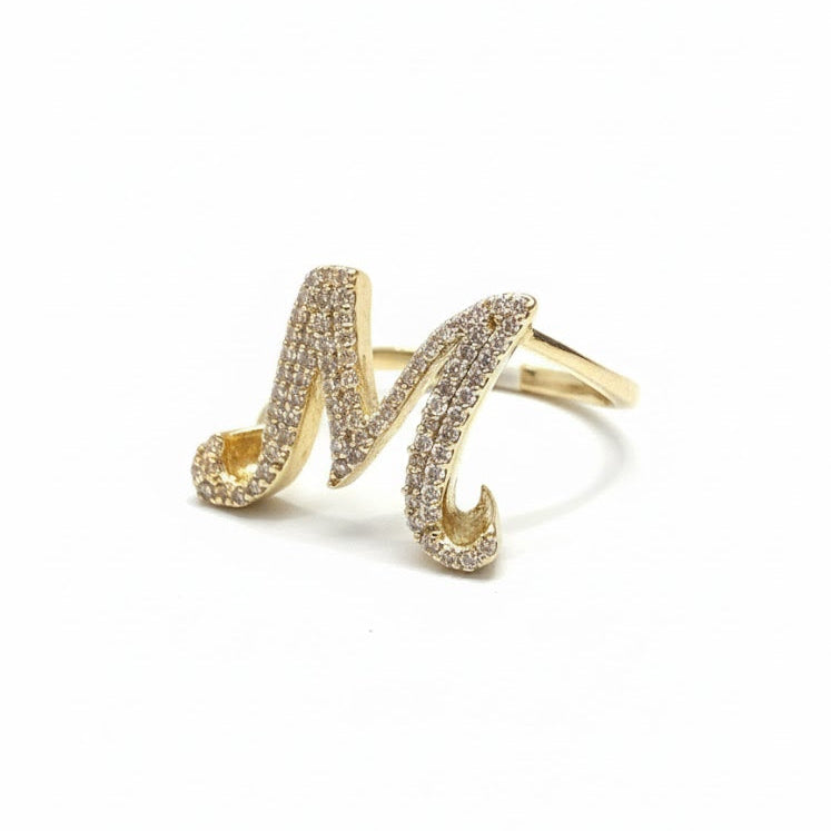 Gold ring with letter 'M' design on a white background