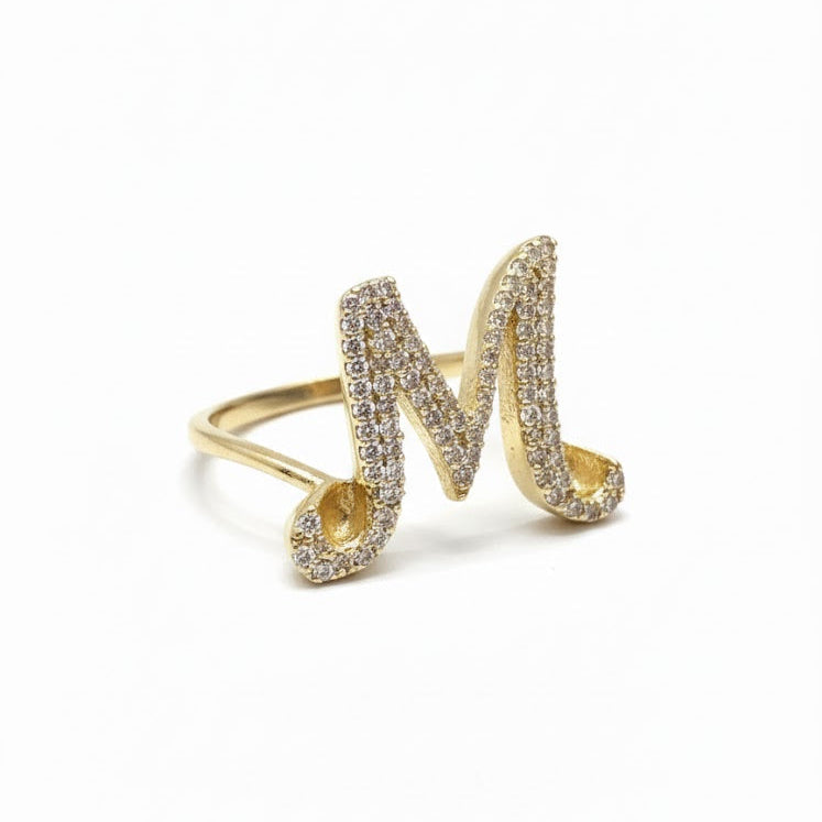 Gold ring with letter 'M' design on a white background