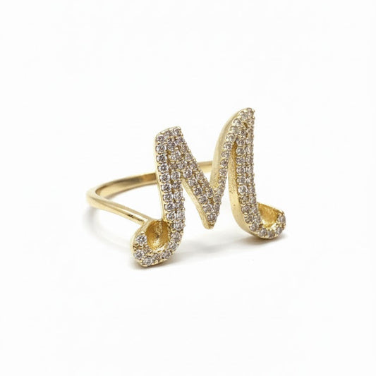 Gold ring with letter 'M' design on a white background